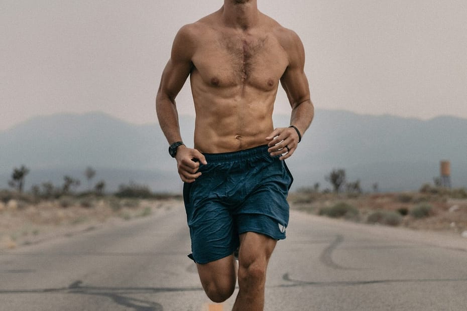 a shirtless man running down a road