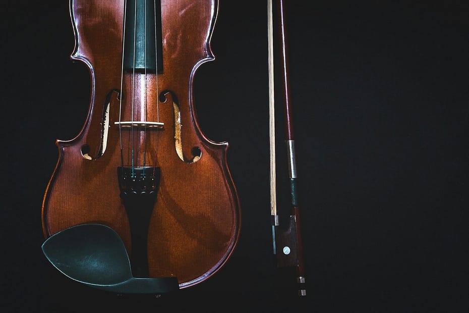 brown violin with bow in black background