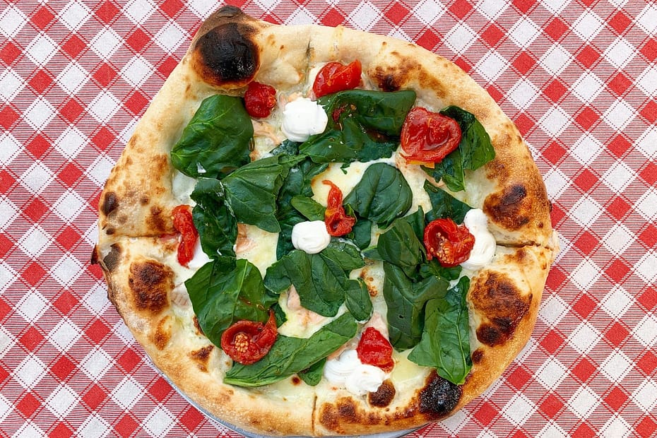 pizza with green leaves on white ceramic plate