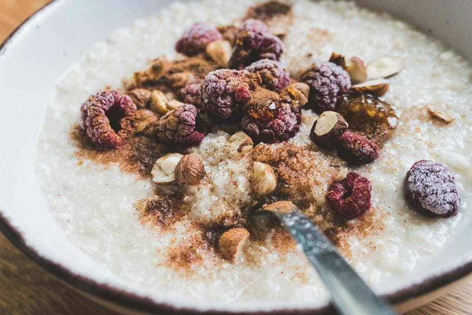 a bowl of oatmeal topped with nuts and raspberries